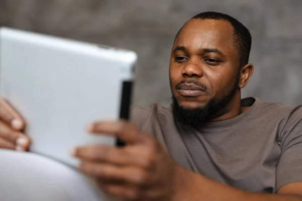 Schwarzer Unrasierter Mann Benutzt Tablet Computer Während Hause Auf Sofa — Stockfoto