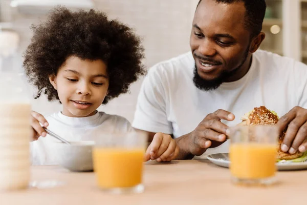 Μαύρος Πατέρας Και Γιος Χαμογελούν Ενώ Τρώνε Πρωινό Στο Σπίτι — Φωτογραφία Αρχείου