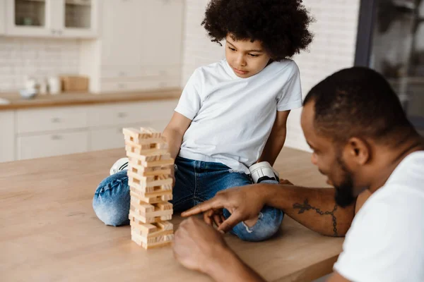Black father and son playing with planks together at home