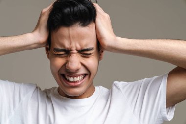 Mutsuz, başı çatık, başı çatık ve başı gri arka planda olan İspanyol bir adam.