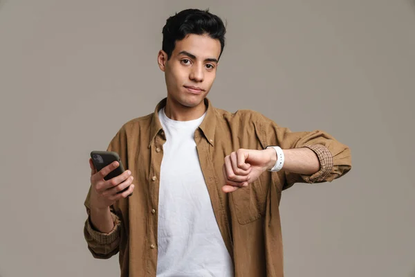 Brunett Hispanic Man Med Mobiltelefon Och Smartwatch Isolerad Över Grå — Stockfoto