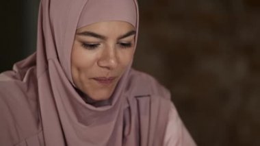Ofiste bir şeyler okurken masasında oturan güzel Arap iş kadınlarının yakın çekim yan görüntüsü.