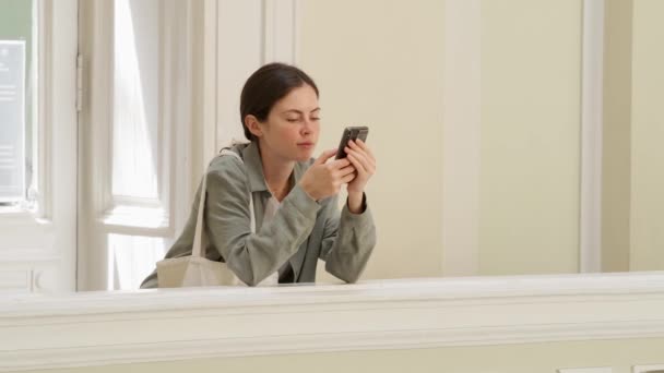 Una Joven Mujer Enfocada Está Usando Teléfono Inteligente Mientras Está — Vídeo de stock