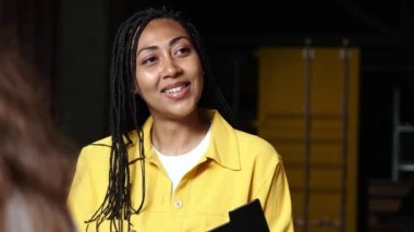 Memnun bir Afro-Amerikalı esmer iş kadını konferans sırasında ofiste oturan iş arkadaşlarıyla konuşuyor.