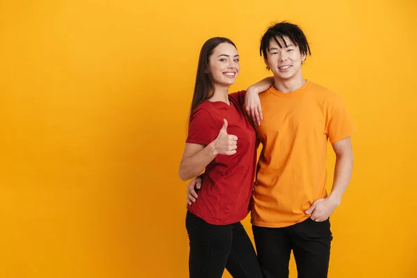 Genç Çok Kültürlü Çift Gülümseyip Kucaklaşırken Başparmaklarını Sarı Duvarın Üzerinde — Stok fotoğraf