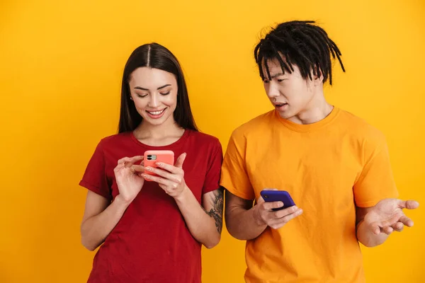 Jovem Casal Multirracial Posando Usando Telefones Celulares Isolados Sobre Parede — Fotografia de Stock