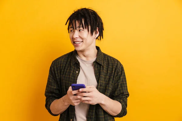 Sorrindo Jovem Asiático Homem Segurando Telefone Celular Enquanto Sobre Fundo — Fotografia de Stock