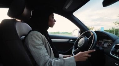Ulusal başörtüsü takan ciddi bir Arap iş kadınının yan görünüşü araba sürüyor