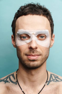 Sarı duvar arka planında kozmetik maske takan orta yaşlı esmer bir adamın fotoğrafını çek.