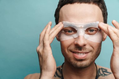 Sarı duvar arka planında kozmetik maske takan orta yaşlı esmer bir adamın fotoğrafını çek.