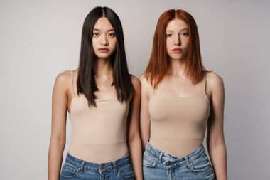 Beyaz duvarın üzerinden izole edilmiş iki kadın poz veriyor ve kameraya bakıyor.
