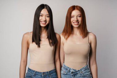 Çok ırklı iki kadın kameraya gülümsüyor ve poz veriyor.