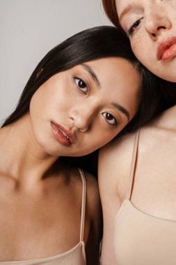 Beyaz duvarın üzerinden izole edilmiş iki kadın poz veriyor ve kameraya bakıyor.