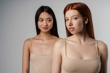 Beyaz duvarın üzerinde poz veren temiz, genç yüzlü iki güzel kızın stüdyo portresini kapat.