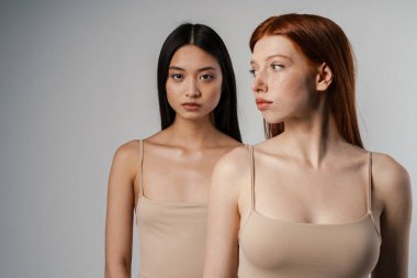 Beyaz duvarın üzerinde poz veren temiz, genç yüzlü iki güzel kızın stüdyo portresini kapat.