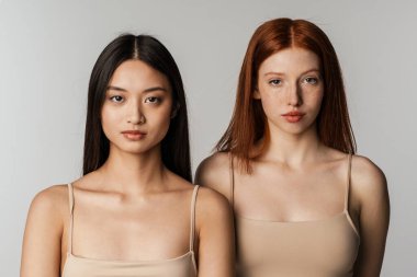 Beyaz duvarın üzerinden izole edilmiş iki kadın poz veriyor ve kameraya bakıyor.