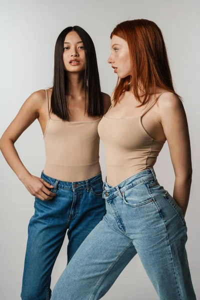 Multirracial Duas Mulheres Jeans Posando Câmera Isolada Sobre Parede Branca — Fotografia de Stock