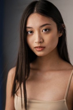 Kapalı alanda poz veren, kameraya bakan Asyalı genç bir kadının yakın çekimi.