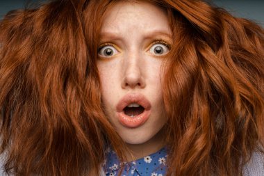 Makyajlı genç kızıl saçlı kadın içeride kameraya şaşırdığını söylüyor.