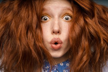 Makyajlı genç kızıl saçlı kadın içeride kameraya şaşırdığını söylüyor.