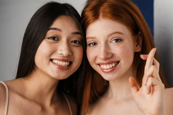 Zwei Lächelnde Junge Multiethnische Frauen Die Zusammen Vor Weißem Wandhintergrund — Stockfoto