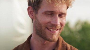 A close-up view of a happy farmer is posing to the camera walking at the greenhouse