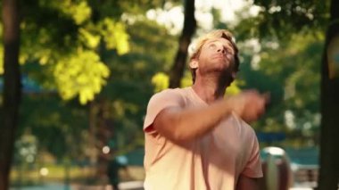 Yakışıklı bir adam yazın parkta badminton oynuyor.