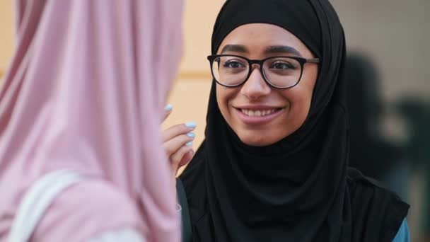 一个戴着国徽的快乐的阿拉伯女人的近照正在和站在街上的朋友说话 — 图库视频影像