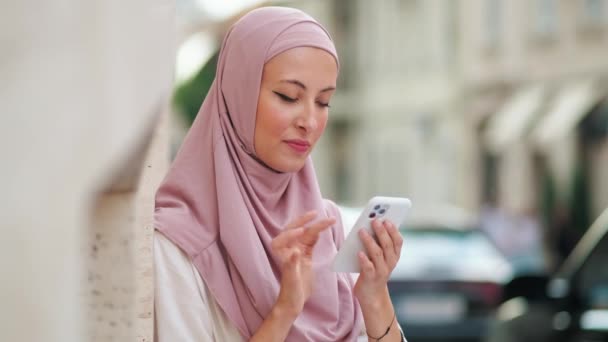 Eine Wunderschöne Arabische Frau Pinkfarbenen Hidschab Plaudert Mit Ihrem Handy — Stockvideo