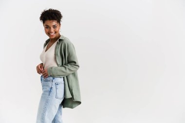 Happy casually dressed young african woman standing over white wall background