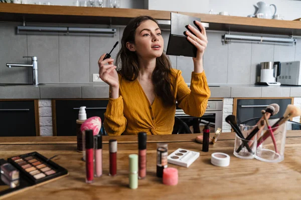 Smiling Young Brunette Woman Doing Makeup While Sitting Kitchen Home — Stock Photo, Image