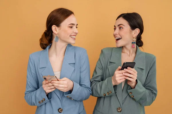 Mladé Dvě Ženy Smějí Při Používání Mobilních Telefonů Izolovaných Přes — Stock fotografie