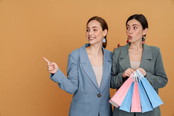 Young Two Women Holding Shopping Bags Pointing Finger Aside Isolated Royalty Free Stock Images