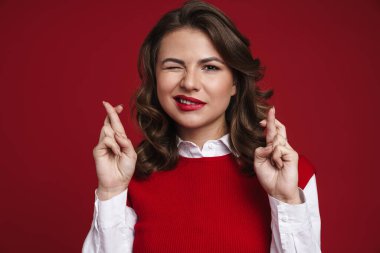 Güzel bir genç kadının kırmızı duvarın arkasında izole bir şekilde el hareketi göstermesi.