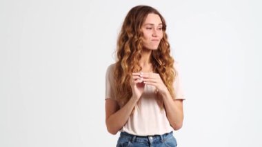 Oyuncu bir kadın, stüdyodaki beyaz bir duvarın ardında gizli bir jest yapıyor.