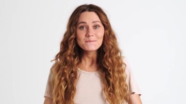 Duygusal açıdan mutlu bir kadının yakın plan görüntüsü stüdyodaki beyaz bir duvarın arkasında izole bir şekilde duran kazanan bir jest yapmaktır.