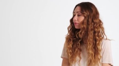 Şaşırmış bir kadın, stüdyodaki beyaz bir duvarın üzerinde duran yan tarafı işaret ediyor.