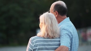 Mutlu yaşlı bir çiftin arka plan görüntüsü. Erkek ve kadın dışarıda yürürken parkın manzarasının keyfini çıkarıyorlar.