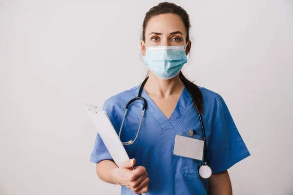 白い背景に隔離された均一な保持ノートパッドを身に着けている自信の若い女性医師の専門家 — ストック写真