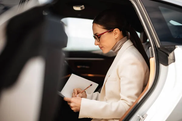 Bonita Mulher Negócios Focada Escrevendo Notas Enquanto Está Sentada Carro — Fotografia de Stock