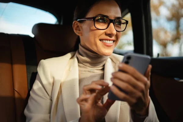 Hermosa Mujer Negocios Sonriente Utilizando Teléfono Móvil Mientras Está Sentado —  Fotos de Stock