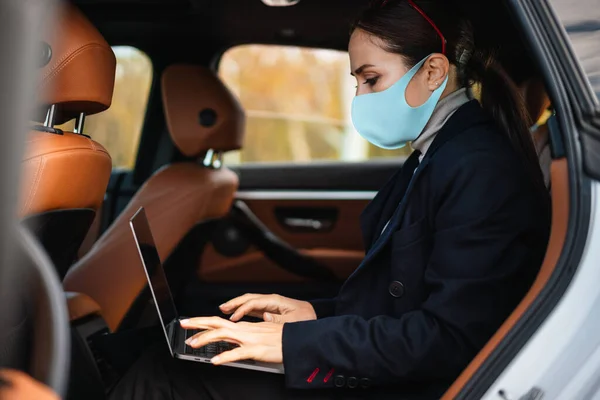 Yüz Maskesi Takan Kendine Güvenen Güzel Kadını Laptopla Arabada Çalışıyor — Stok fotoğraf