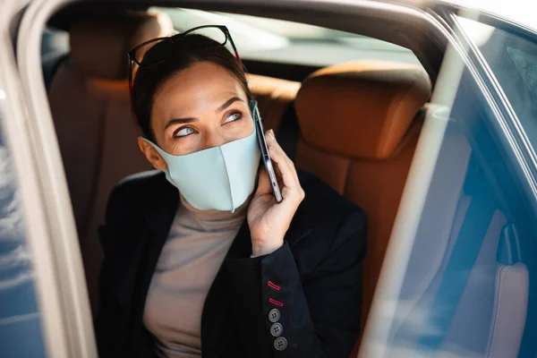 Yüz Maskesi Takan Güzel Kadını Arabada Otururken Cep Telefonuyla Konuşuyor — Stok fotoğraf
