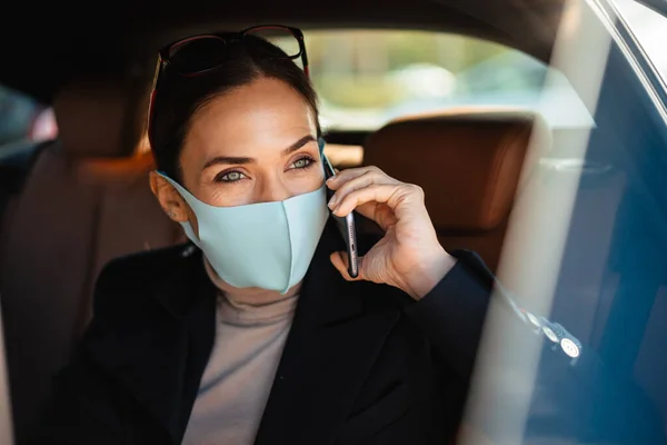 Yüz Maskesi Takan Güzel Kadını Arabada Otururken Cep Telefonuyla Konuşuyor — Stok fotoğraf