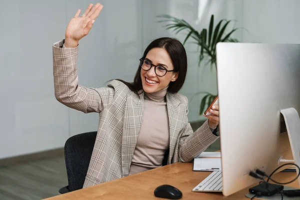 Pleased Charming Woman Waving Hand Using Cellphone While Working Office — Stock Photo, Image