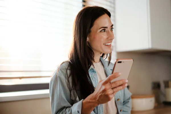 Lachende Aantrekkelijke Jonge Vrouw Sms Mobiele Telefoon Keuken — Stockfoto