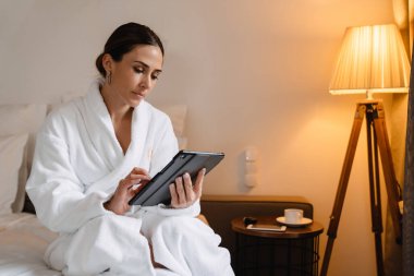 Gülümseyen orta yaşlı esmer, bornozlu beyaz kadın.