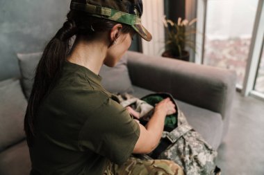 Kanepede oturan ciddi ve güzel asker kadın.