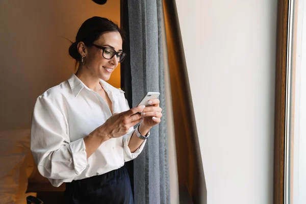 Smilende Middelaldrende Brunette Hvit Forretningskvinne Smarte Klær Som Står Vinduet – stockfoto