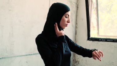 A beautiful arabian sports woman wearing national hijab is measuring her pulse while using a fitness tracker